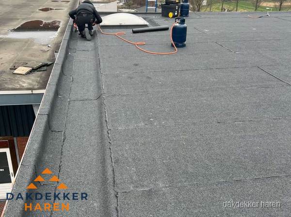 Dakdekker repareert bitumen dakbedekking op groot plat dak in Haren Dakdekker repareert bitumen dakbedekking op groot plat dak in Haren